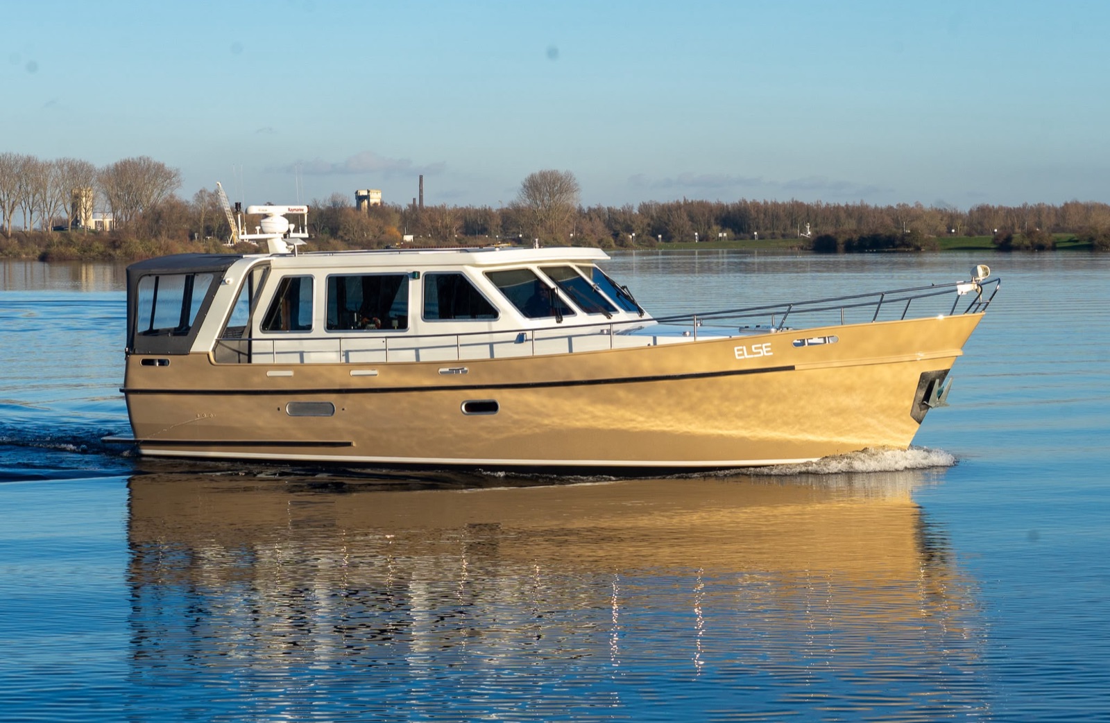 Goudkleurig gespoten motorjacht vaart in het gouden uur